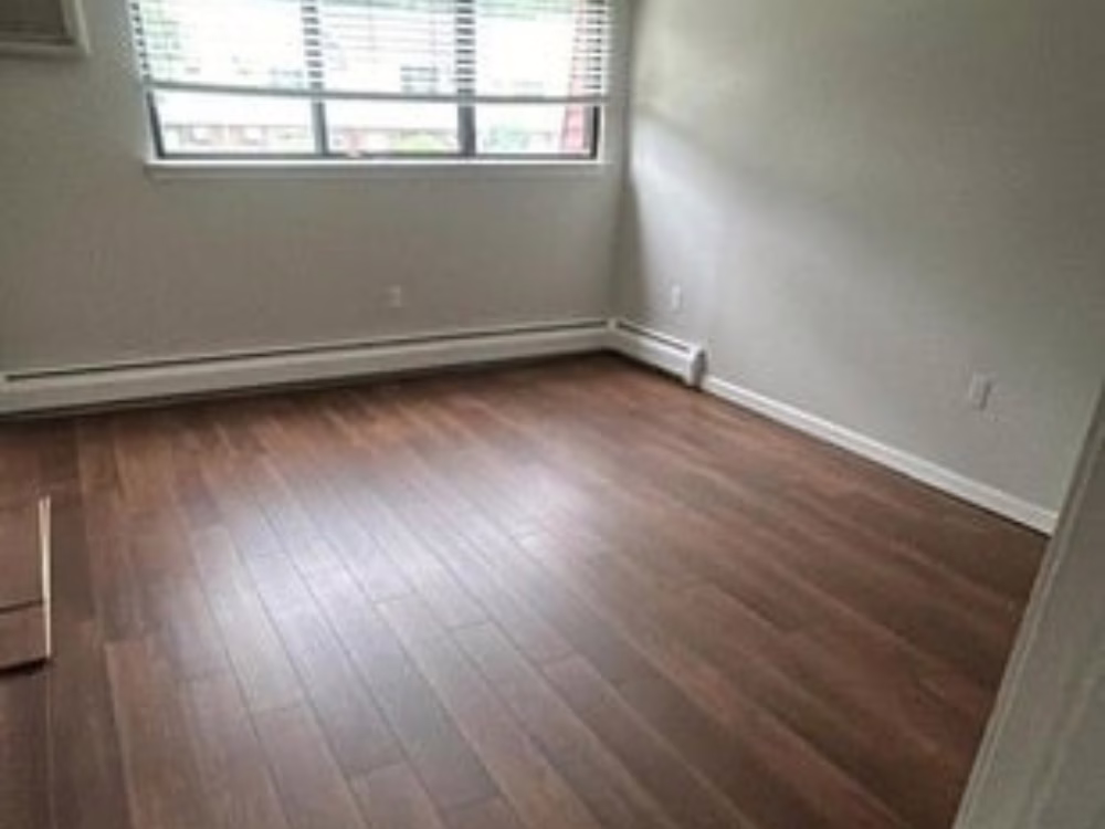 Finished bedroom with new wood-style flooring after a professional flooring installation in Newington, CT.