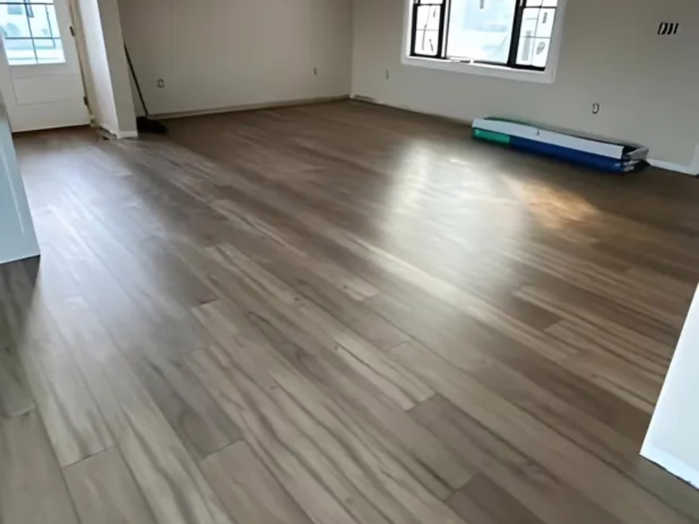 Open living room with newly installed wooden floors, highlighting floor installation and recoating services.