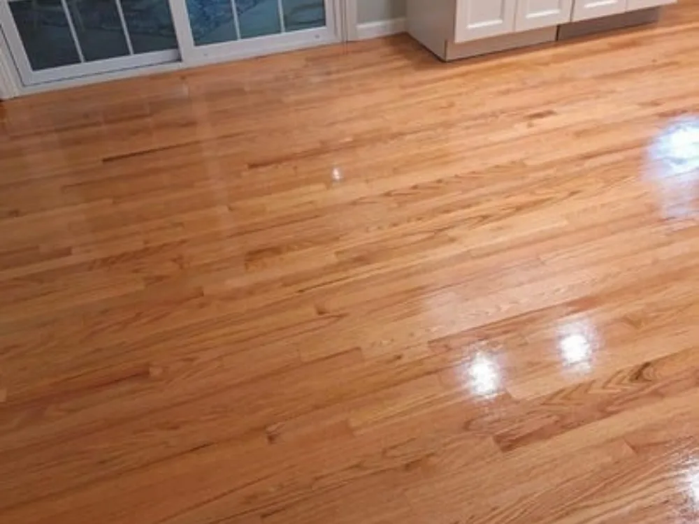 Hardwood floor refinishing with polished finish near kitchen cabinets.