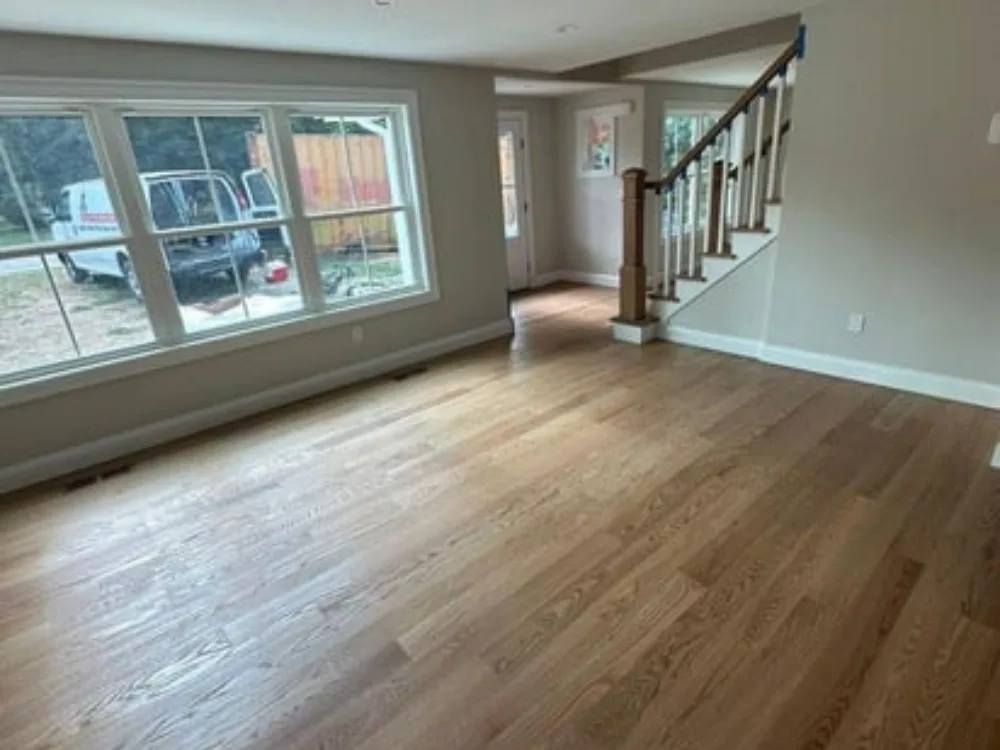 Hardwood floor installation in spacious living room with large windows
