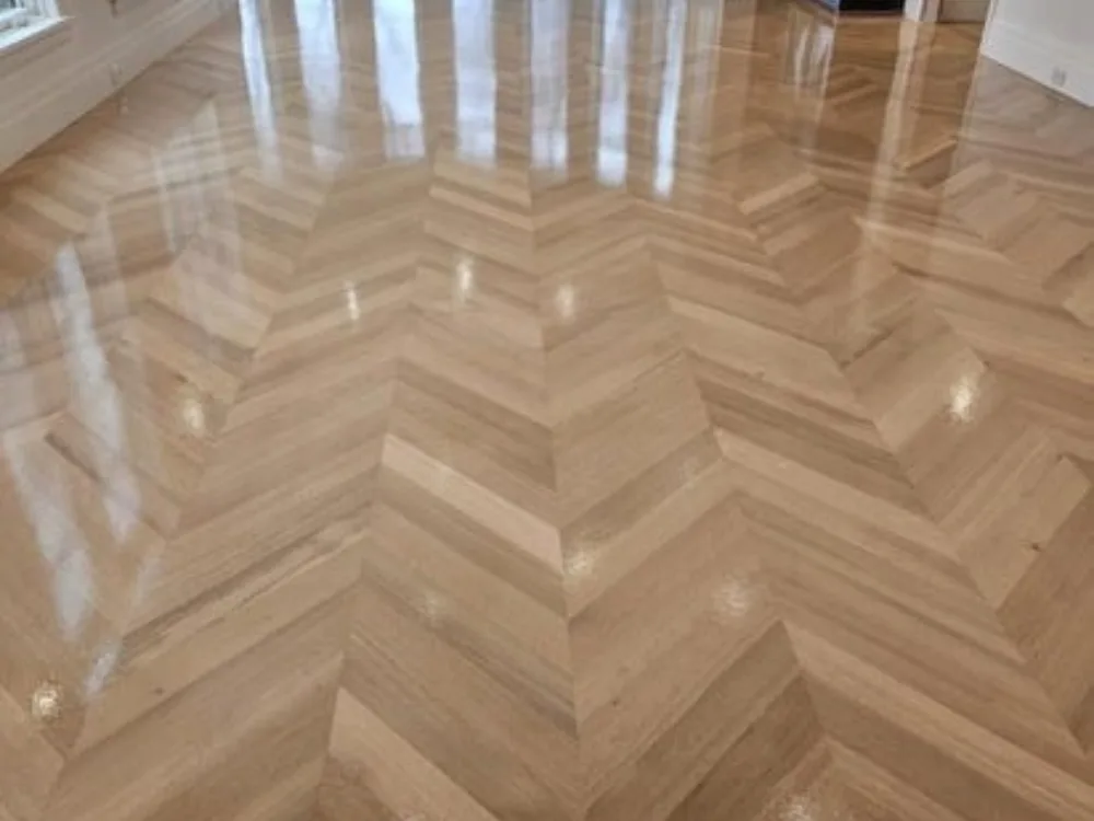 Chevron wood flooring with polished finish in bright living room.