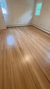 Wood floor refinishing in Wethersfield, with a glossy finish in a bright room after restoration.
