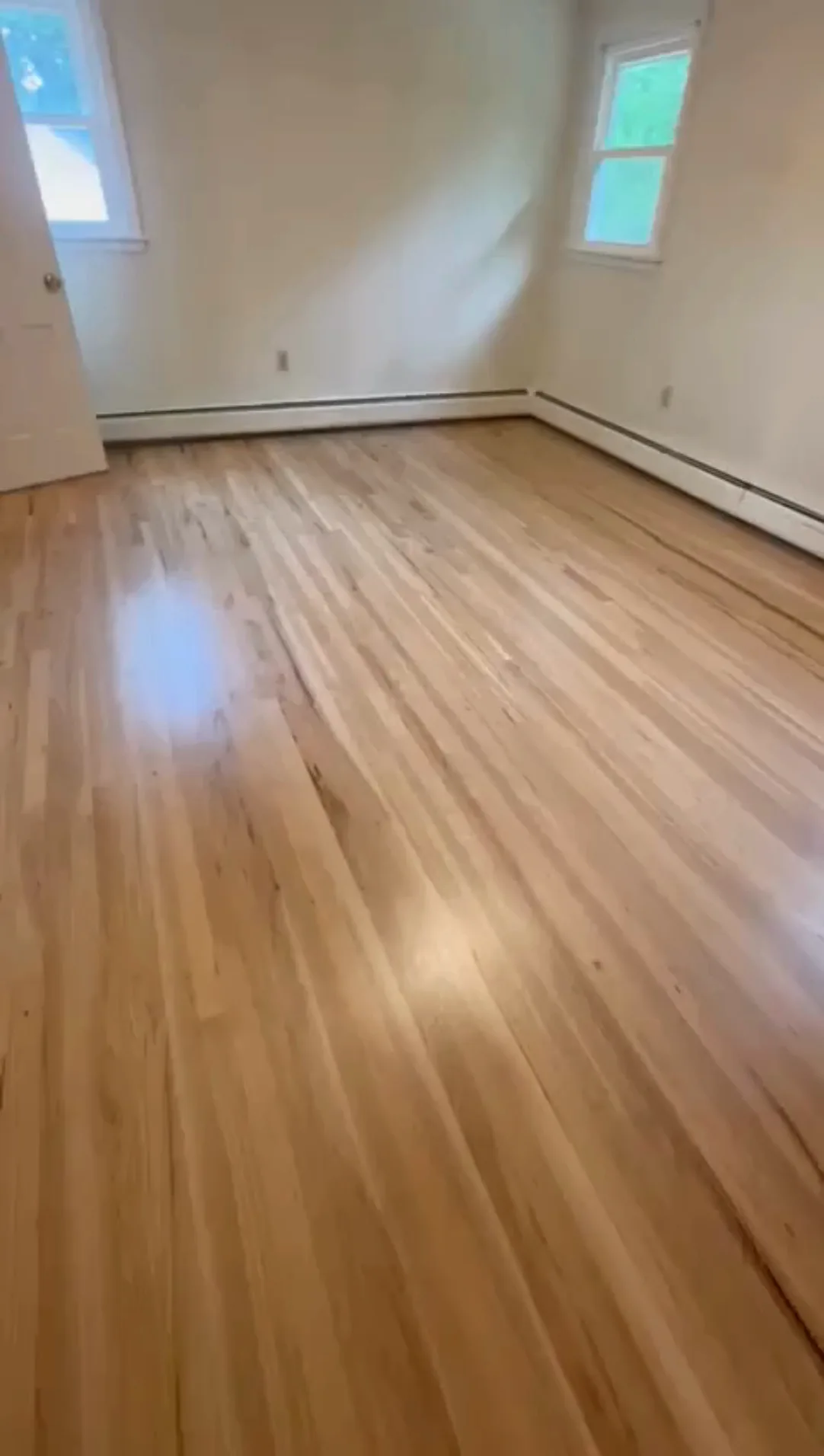 Wood floor refinishing in Wethersfield, with a glossy finish in a bright room after restoration.