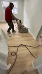 Technician performing hardwood floor sanding with a floor sander.