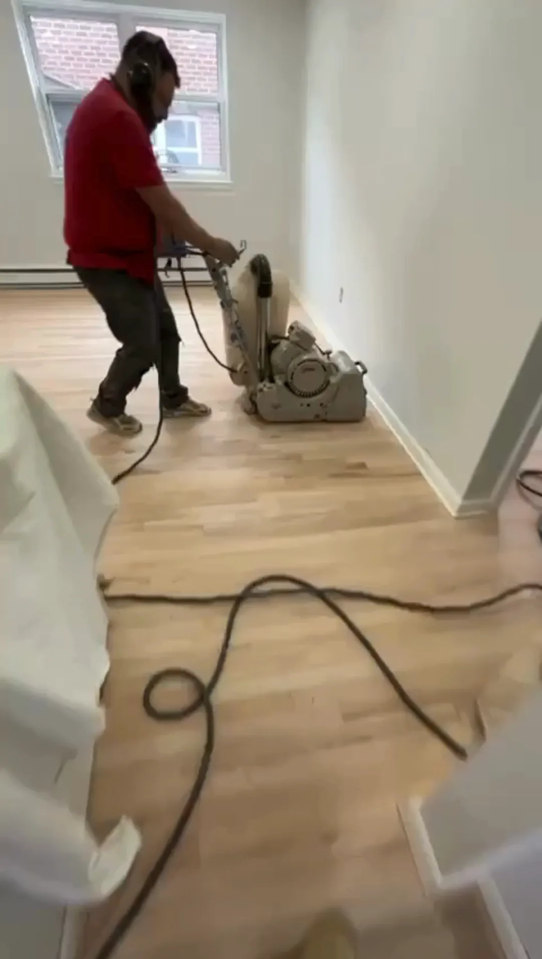 Technician performing hardwood floor sanding with a floor sander.