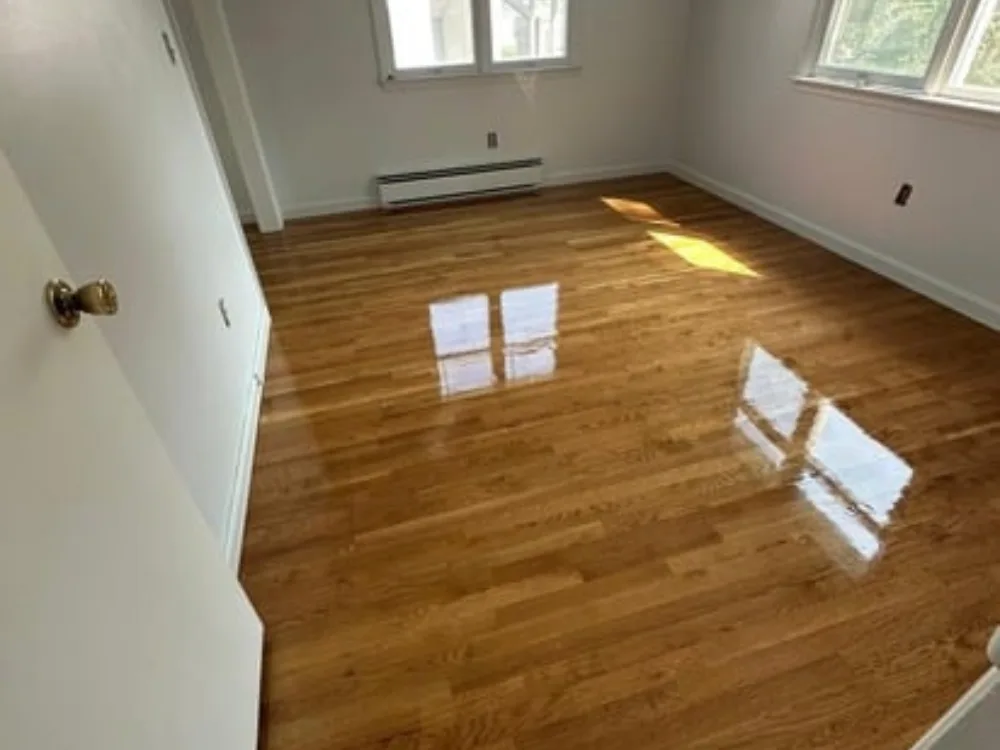 Hardwood floor refinishing in an empty bedroom with natural light