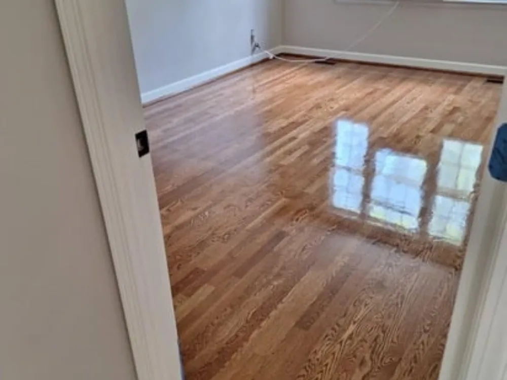 View of a room with recently completed hardwood floor refinishing, showing a high-gloss finish.