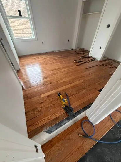 A Farmington CT hardwood installation in progress, highlighting the professional flooring nailer and a completed section.