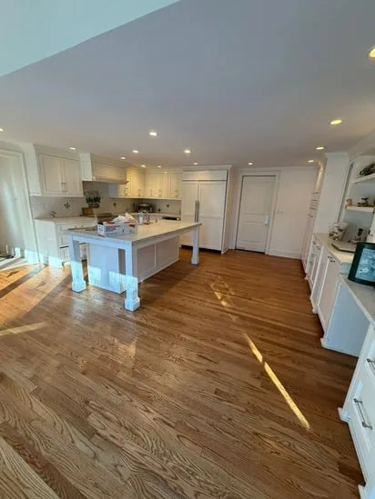 Kitchen interior shot emphasizing the protective coating texture and uniform shine of the hardwood floor sand finish.